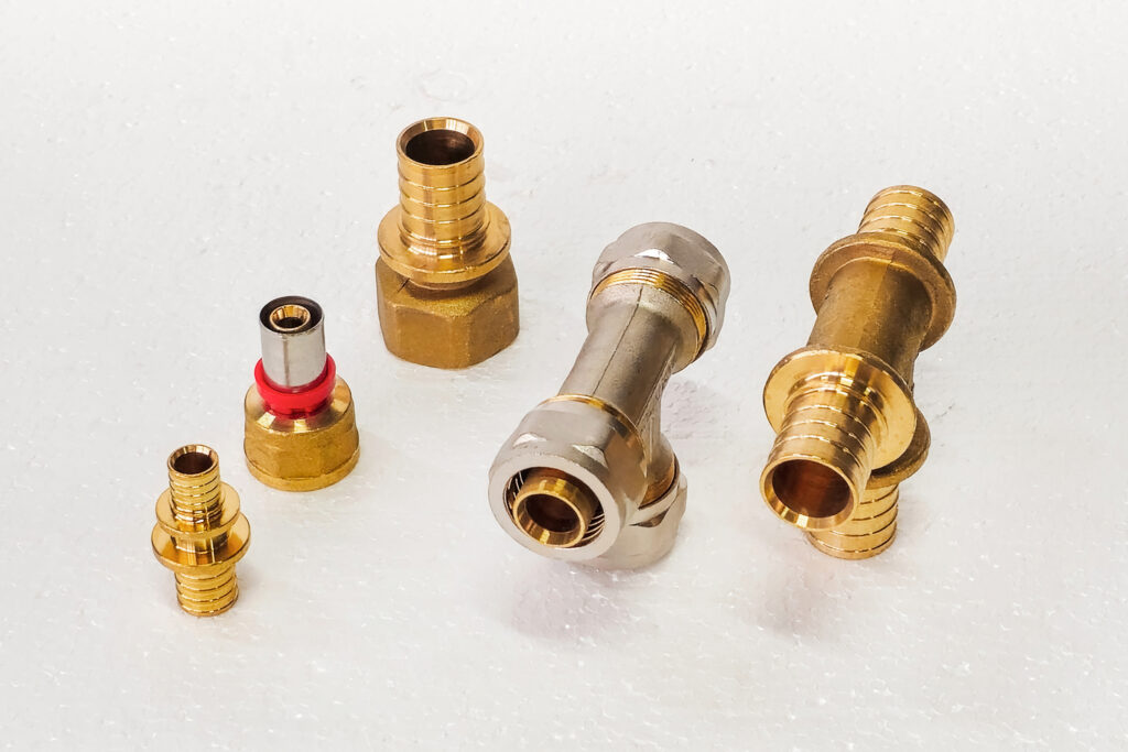 Copper and brass plumbing fittings for connection pipes on white foam. Close up. Copy space.