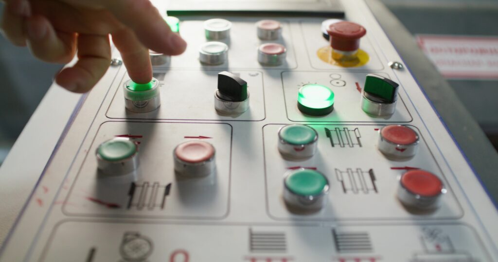A man presses the machine control button while working in a factory. Close-up of his hands, an unrecognizable person